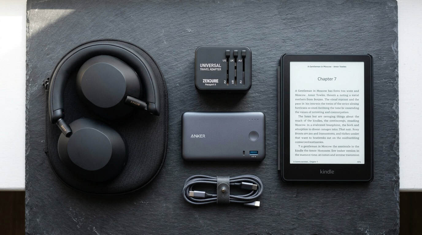 Best travel accessories flatlay including universal adapter, power bank, and noise-cancelling headphones